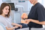 a dentist is showing a lady dental implants demo