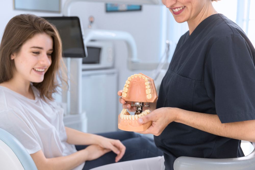 a dentist is showing a lady dental implants demo