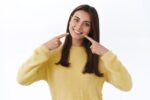 a lady is pointing towards here teeth